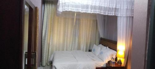 a bedroom with a white bed with a window at Jakicha Motel in Dar es Salaam