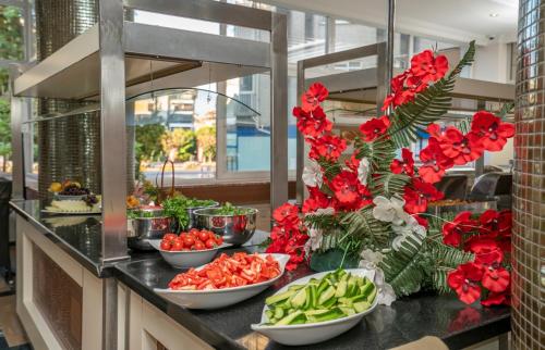 ein Buffet mit Schüsseln voller Gemüse und roten Blüten in der Unterkunft Carmen Suite Hotel in Alanya
