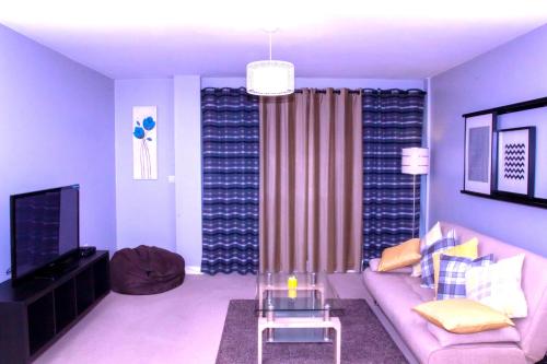 a living room with a couch and a tv at Allen Luxury Apartment in Coventry