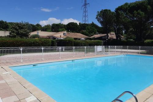 une grande piscine bleue à côté d'une clôture dans l'établissement Mazet dans résidence avec piscine, à Bagnols-en-Forêt