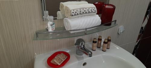 a bathroom with a sink with a mirror and towels at MARIANA - guest rooms in Gotse Delchev