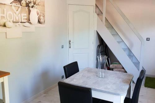 a dining room with a table and chairs and a staircase at Joli Studio confort indépendant coeur de Sologne in Lamotte-Beuvron