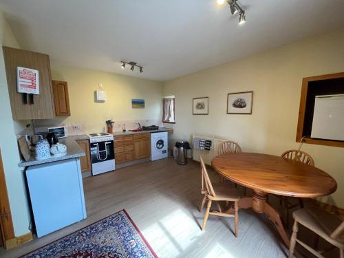 a kitchen with a wooden table and a dining room at West Gorton in Grantown on Spey
