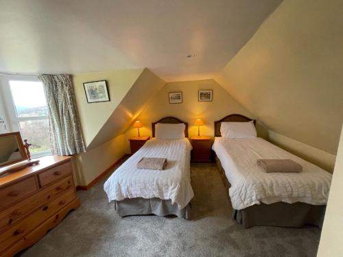 a bedroom with two beds and a tv and a window at West Gorton in Grantown on Spey