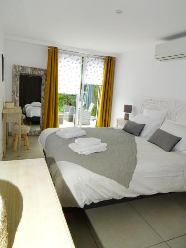 a bedroom with a large white bed with yellow curtains at LUVA d'Azur, Rez de villa LE RIOU - LE VALLON in Le Bar-sur-Loup
