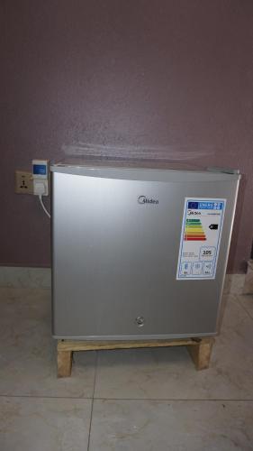a silver refrigerator sitting on a floor next to a wall at Jakicha Motel in Dar es Salaam