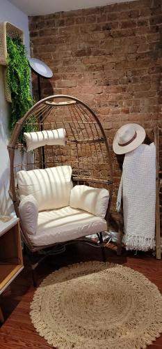 a rattan chair in a room with a brick wall at LUXE BROOKLYN Getaway in Brooklyn