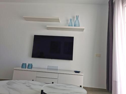 ein Wohnzimmer mit einem TV an einer weißen Wand in der Unterkunft Luxury Apartment On The Beach in Playa Honda