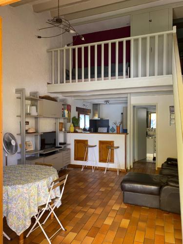Il comprend un salon avec une table et une cuisine avec une mezzanine. dans l'établissement Jolie maison de village, à 2 min à pied du lac d'Esparron de Verdon, à Esparron-de-Verdon
