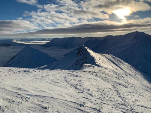 a snow covered mountain with the sun in the background at Glenfalloch Beag Apartment, Torvaig in Portree
