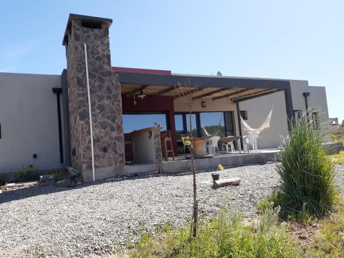 a house with a stone pillar in front of it at sueño del chocon in Villa El Chocón