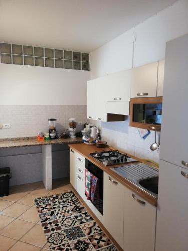a kitchen with white cabinets and a stove top oven at Soggiorni Dana B&B in Duino