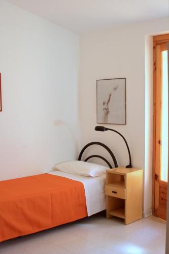 a bedroom with a bed with an orange blanket and a lamp at Residence Villa Agrimare in Vieste