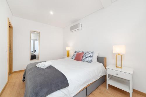 a white bedroom with a bed and a night stand at Varandas do Sítio - By SCH in Nazaré