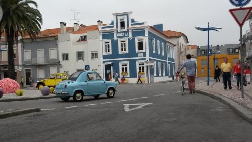 stary niebieski samochód i mężczyzna na rowerze na ulicy w obiekcie Aveiro Rossio Hostel w mieście Aveiro