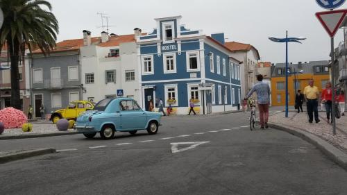 Una vecchia macchina blu e un uomo in bicicletta per strada di Aveiro Rossio Hostel ad Aveiro