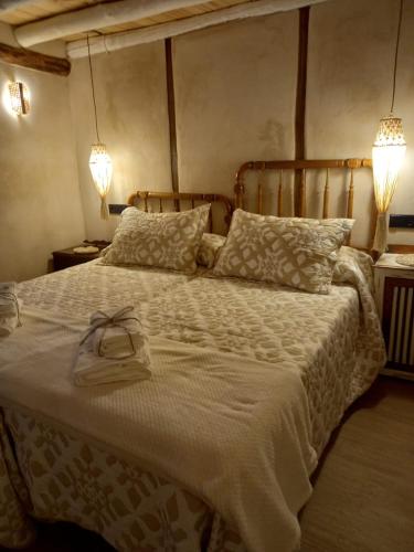 a bedroom with a bed with a white blanket and two lights at La Herrerita in Candelario