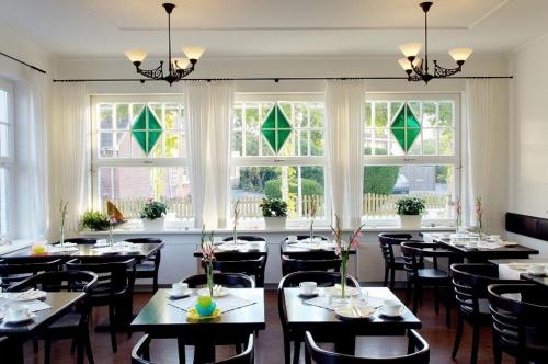 a dining room with tables and chairs and windows at Hotel Seemöwe in Grömitz