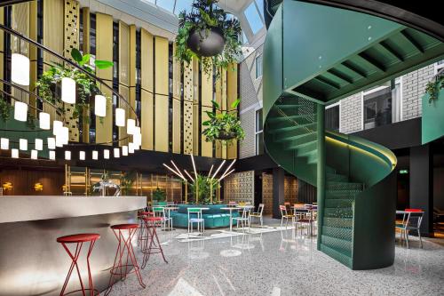 a lobby with a staircase and tables and chairs at The Florian Amsterdam Schiphol Airport, WorldHotels Crafted in Hoofddorp