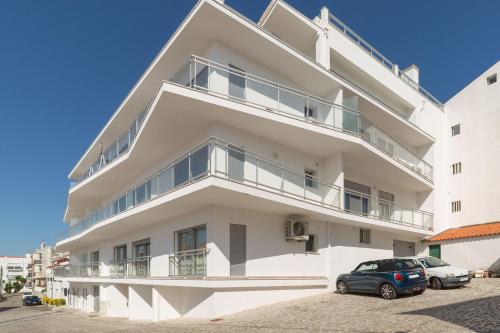 a white building with cars parked in front of it at Varandas do Sítio - By SCH in Nazaré