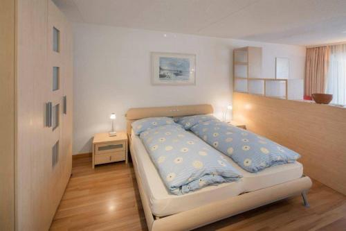 Cette chambre comprend un grand lit avec des draps bleus et une table de nuit. dans l'établissement Cristal 50, à Loèche-les-Bains