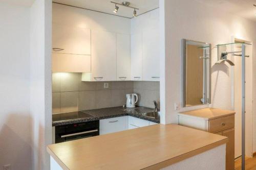 une cuisine avec des placards blancs et un comptoir en bois dans l'établissement Cristal 50, à Loèche-les-Bains