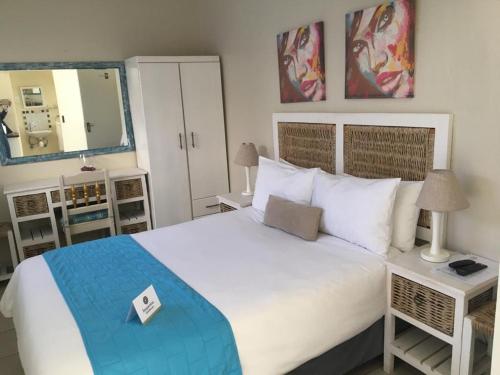 1 dormitorio con 1 cama blanca grande y espejo en Kayamina Guesthouse, en Honeydew