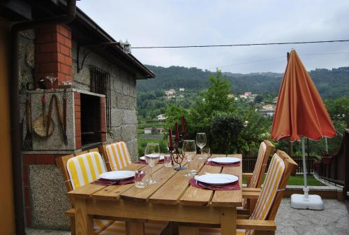 a wooden table with chairs and an orange umbrella at Leiras do Seixo - Casa dos Tinos in Amarante