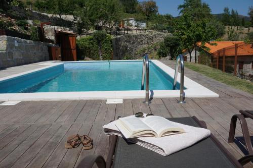 a book sitting on a table next to a swimming pool at Leiras do Seixo - Casa dos Tinos in Amarante