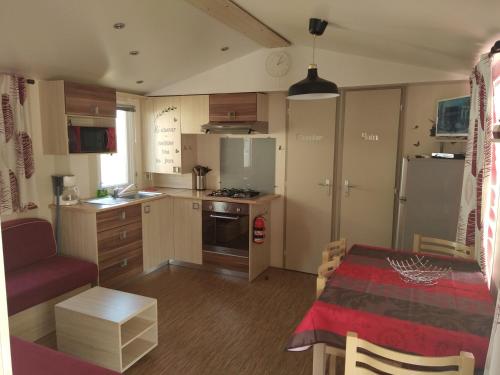 une petite cuisine avec une table et un canapé rouge dans l'établissement Mobilhome camping proche des plages, à Saint-Jean-de-Monts