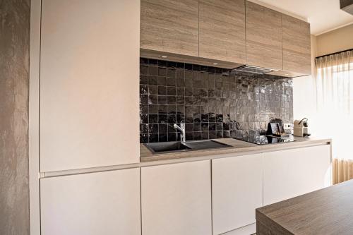 a kitchen with white cabinets and a sink at Apart! & Moment! in De Haan