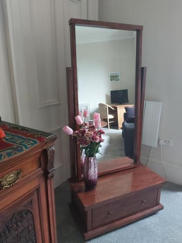 a vase of flowers on a table in front of a mirror at Kirkhouse in Wick