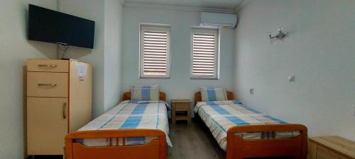 um quarto com duas camas e uma televisão e duas janelas em NANE em Kruševo