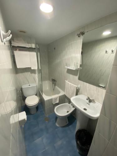 a bathroom with a toilet and a sink and a bath tub at Pensión Eurosol in Granada