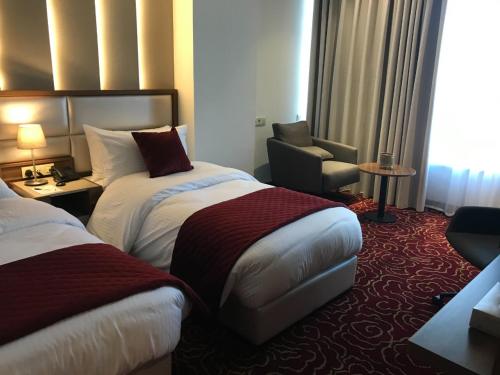 a hotel room with two beds and a chair at Lilac Hotel - Amman in Amman