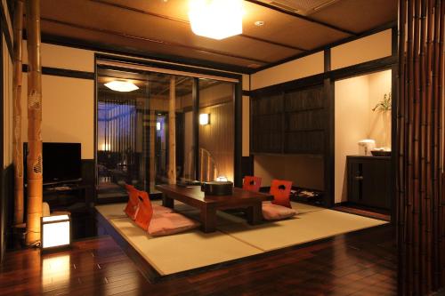 a living room with a table and orange chairs at Bettei Soan in Minami Aso