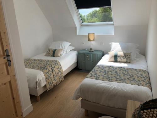 twee bedden in een kleine kamer met een raam bij chambre d'hôtes Le Domaine de la Vallée in Saint-Martin-de-Varreville