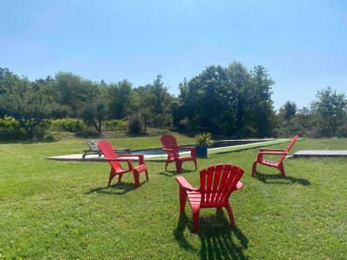 a group of red chairs sitting in the grass at 1832 La Rabassière in Malaucène