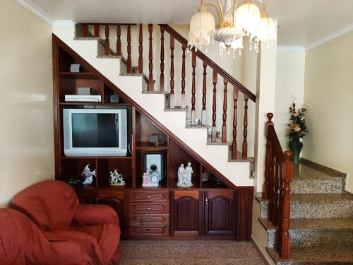 uma sala de estar com uma escada com uma televisão e uma cadeira em Casa do Terço em Câmara de Lobos
