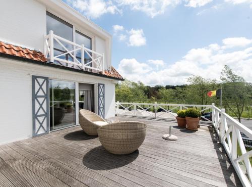 a deck with two chairs and chairs on a house at Lebeaubylivingroom Hotel in Knokke-Heist