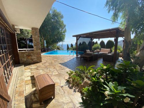a patio with a bench and a pavilion next to a pool at Luxury villa with stunning panoramic sea view in Keratea