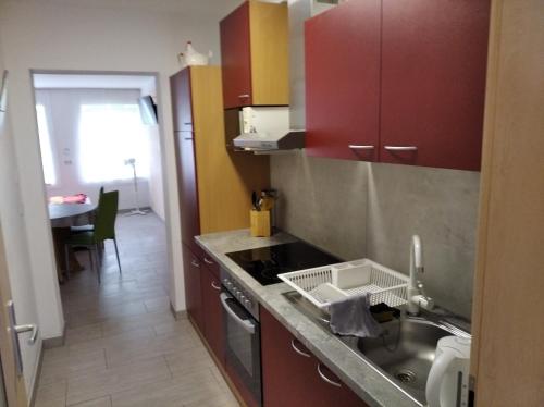 eine Küche mit roten Schränken, einer Spüle und einem Tisch in der Unterkunft Ferienwohnung Sowade in Nebra
