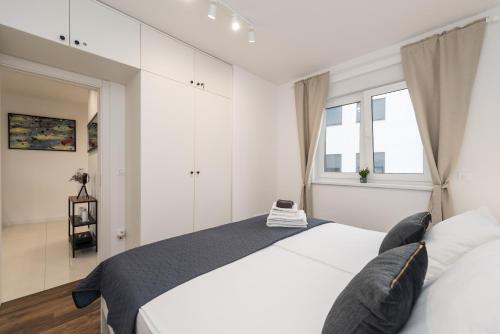 a white bedroom with two beds and a window at Apartman Enjoy Nin in Nin
