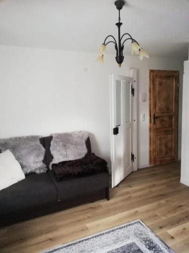 a living room with a black couch and a wooden floor at Ochsenhof in Feuchtwangen