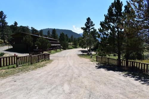 a dirt road next to a fence and trees at Estes Lake Lodge in Estes Park