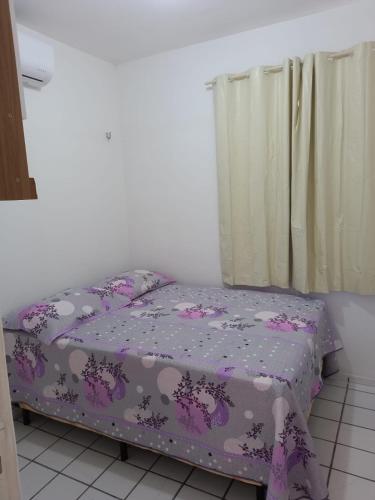 a bed in a room with a purple comforter at Solaris Sul in Teresina