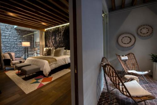 a bedroom with a bed and chairs in a room at Casa Cien Hilos in San Miguel de Allende