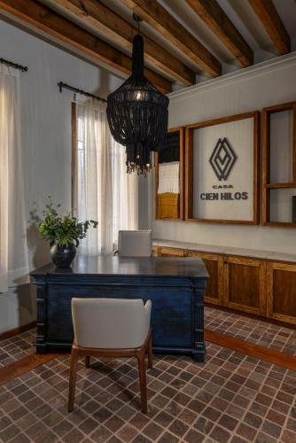 a desk in a room with a chair and a chandelier at Casa Cien Hilos in San Miguel de Allende