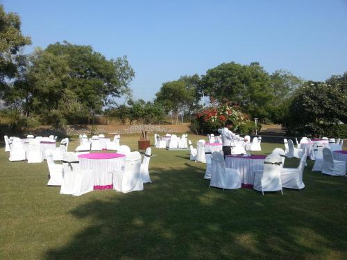 a group of white tables and chairs in a field at The Meadows Resort and Spa in Aurangabad