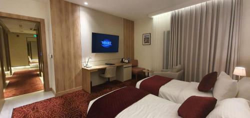 a hotel room with two beds and a desk at Lilac Hotel - Amman in Amman